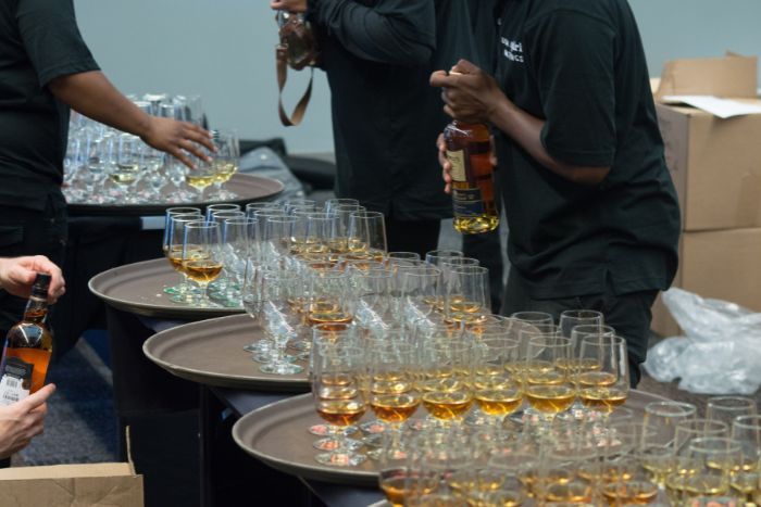A flight of Whiskey being poured A flight of Whiskey being poured